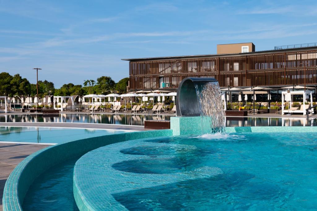 a fountain in a pool in front of a building at Lino delle Fate Eco Resort in Bibione