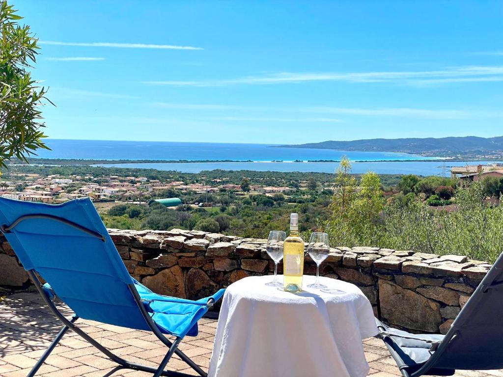 un tavolo con una bottiglia di vino e due sedie di VILLA Lu FRAILI IMMERSA NELLA NATURA VISTA MARE a Nuragheddu