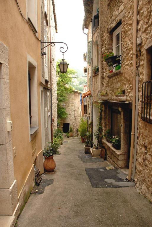 une allée entre deux bâtiments en pierre avec des plantes dans l'établissement Joli havre de paix, à Vence
