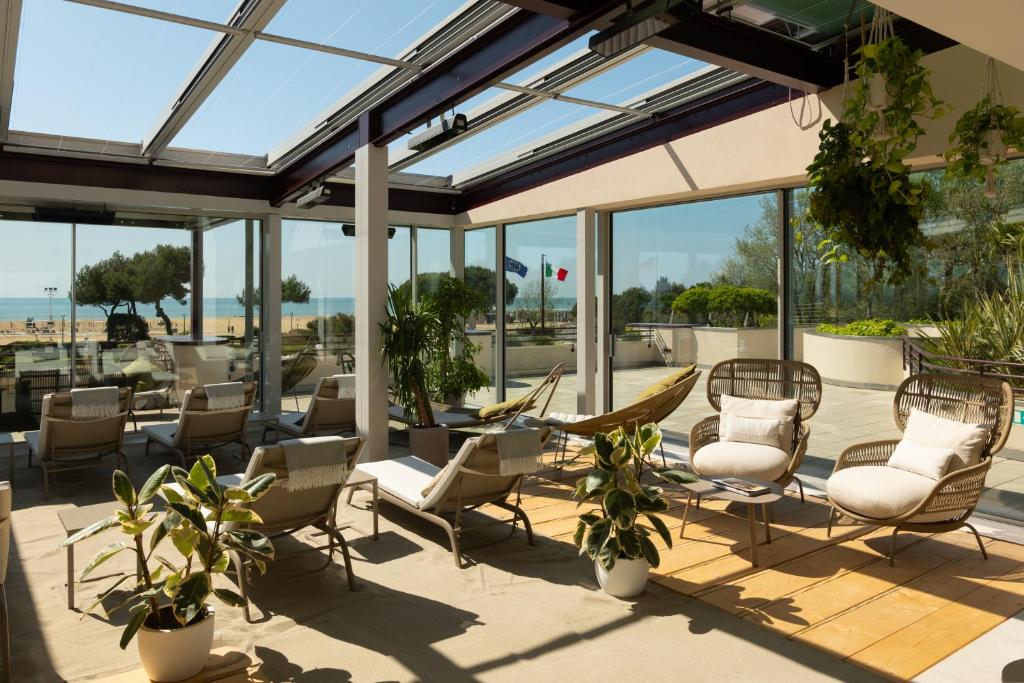 a patio with chairs and tables and windows at Savoy Beach Hotel & Thermal Spa in Bibione