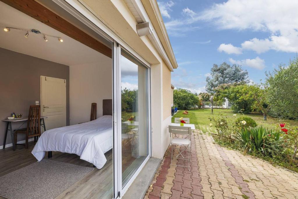 a bedroom with a bed and a view of a garden at Les Lilas in Podensac