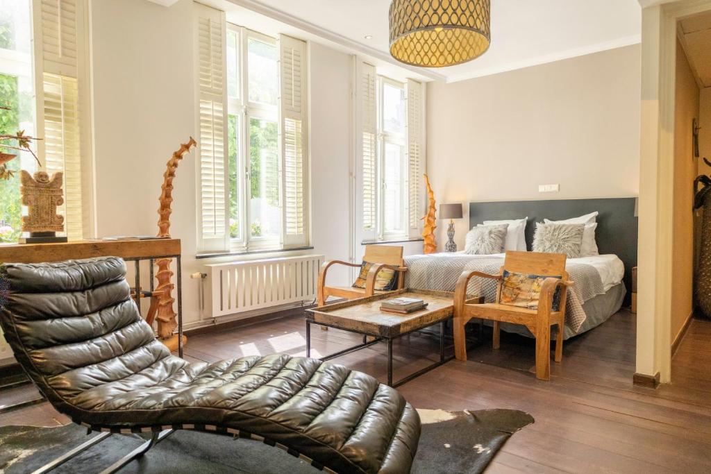 uma sala de estar com uma cama, uma mesa e cadeiras em Bouteaque Hotel em Maastricht