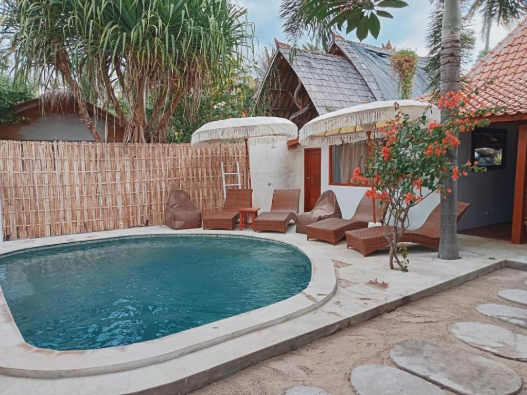 龍目島的住宿－Ardi Beltza Hotel and Private Pool Villa，后院的游泳池,带椅子和房子