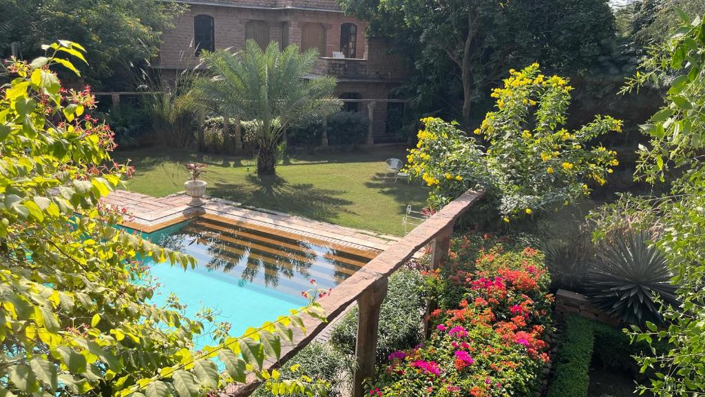 un giardino con ponte sopra una piscina fiorita di Devi Bhawan - A Heritage Hotel a Jodhpur