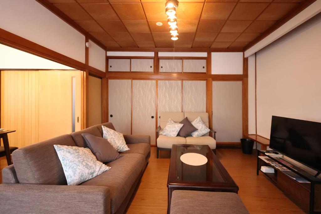 sala de estar con sofá y TV en くつろぎのお宿 やわや toyama en Sakurabashidōri