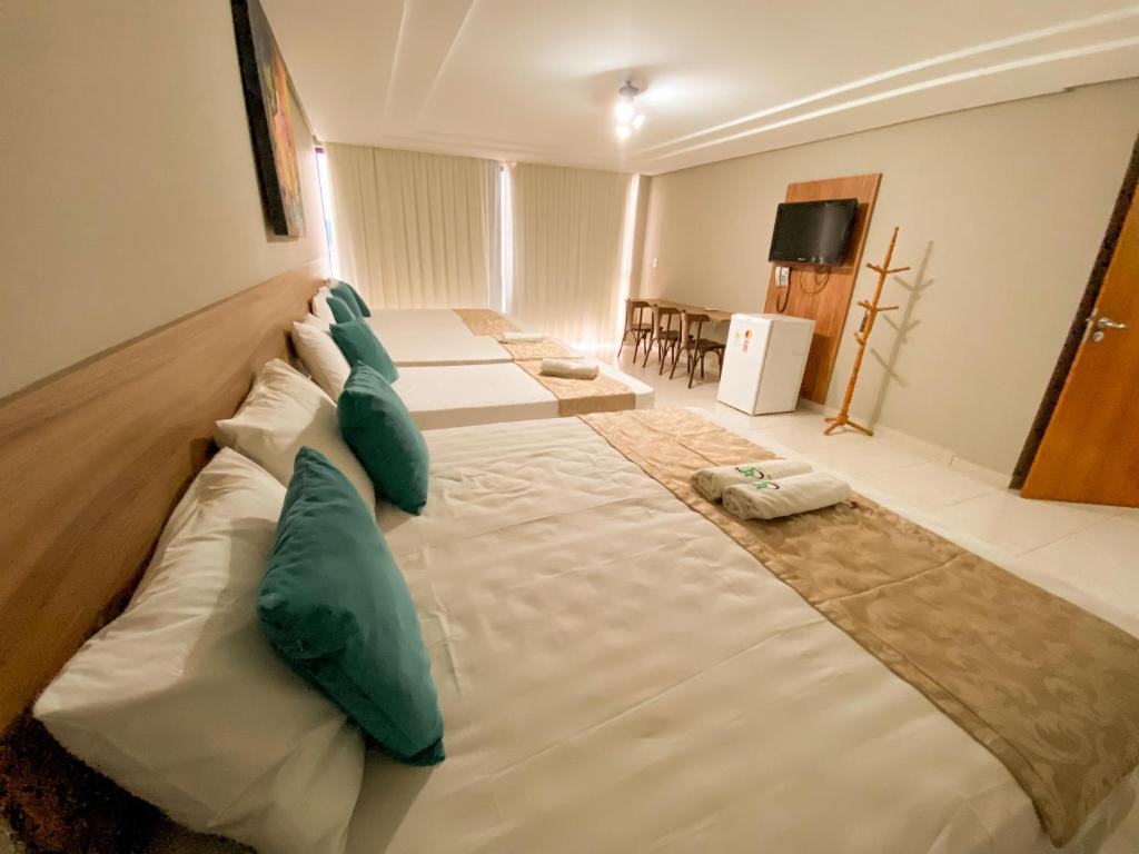 een groot bed in een hotelkamer met groene kussens bij Hotel Cantinho Verde in Teixeira de Freitas