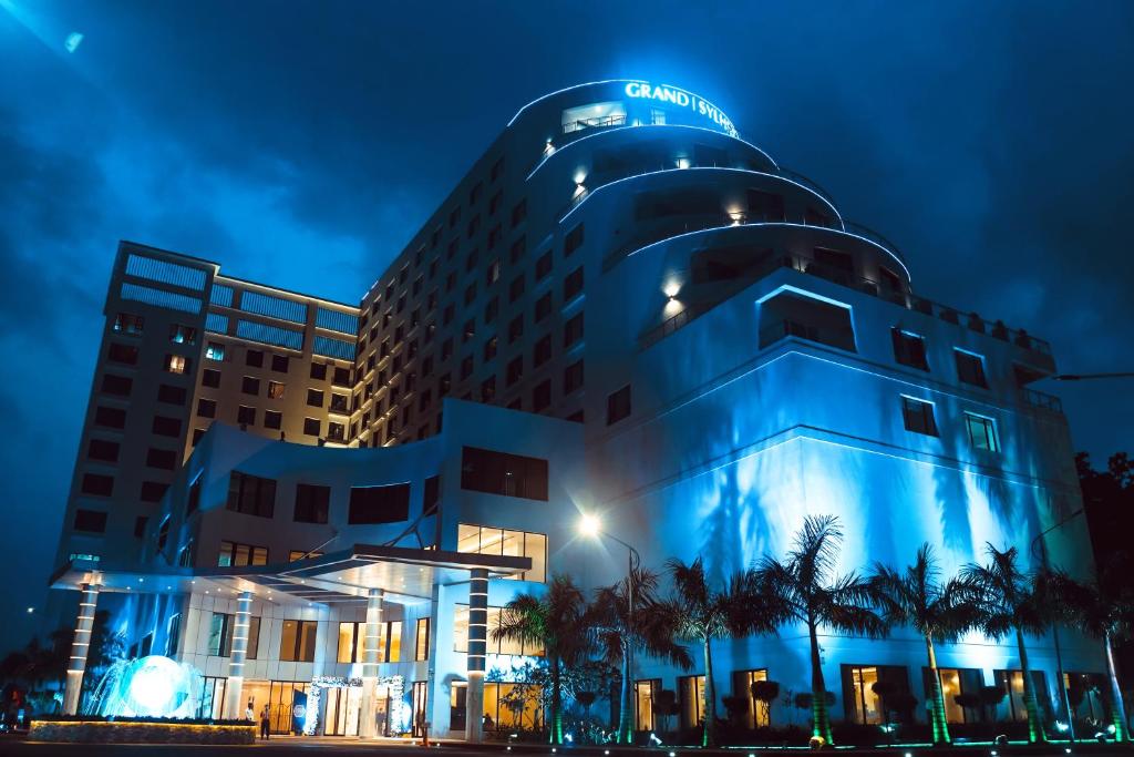 um hotel com um edifício azul à noite em Grand Sylhet Hotel & Resort em Sylhet