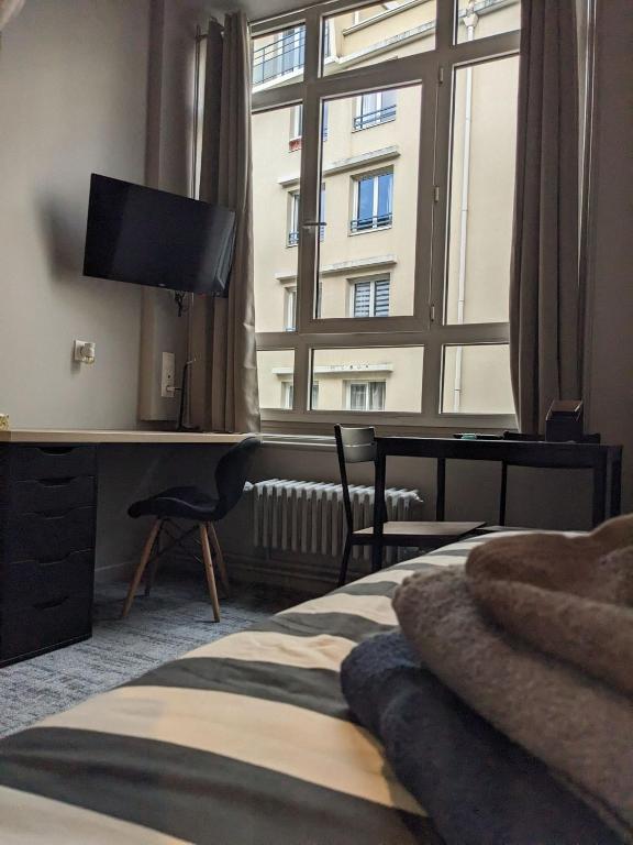 une chambre avec un lit et un bureau et une grande fenêtre dans l'établissement Le 12 cosy wifi et parking gratuit 7b, à Saint-Étienne