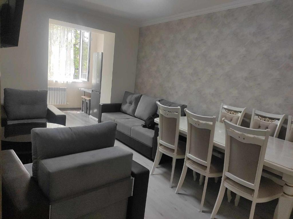 ein Wohnzimmer mit einem Sofa, einem Tisch und Stühlen in der Unterkunft Городской эдем: уют и комфорт in Yerevan