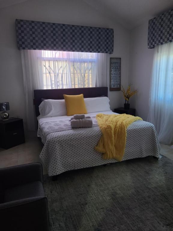 1 dormitorio con 1 cama con sábanas amarillas y ventana en Caribbean Estates, 10 mins from the Beach, Beautiful Gated Community en Portmore