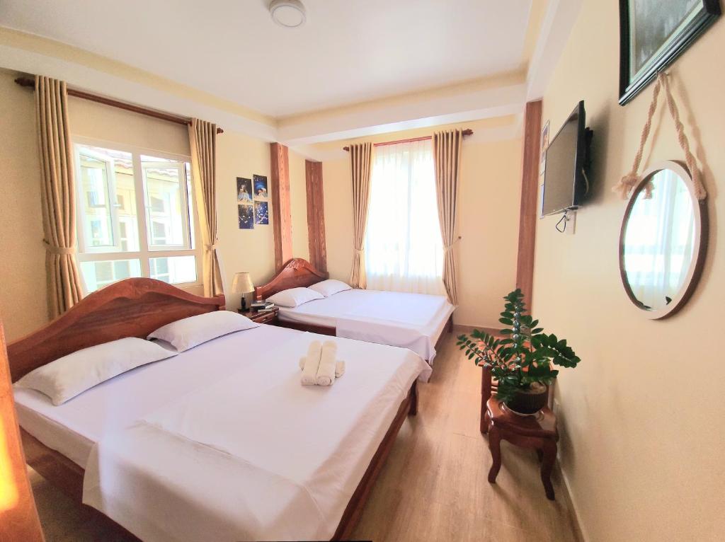 a hotel room with two beds and a mirror at Bình Đào Hotel - Khách sạn ngay trung tâm giá rẻ in Da Lat
