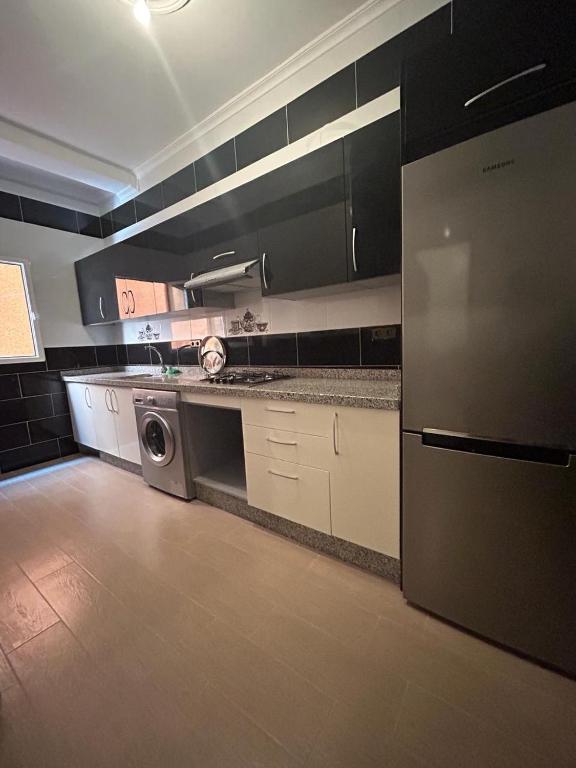 a kitchen with white cabinets and a washer and dryer at Appartement à Houma, proche Port Tanger Med in Dalia