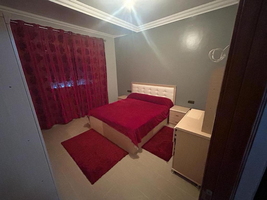 a small room with a red bed and a window at Appartement à Houma, proche Port Tanger Med in Dalia