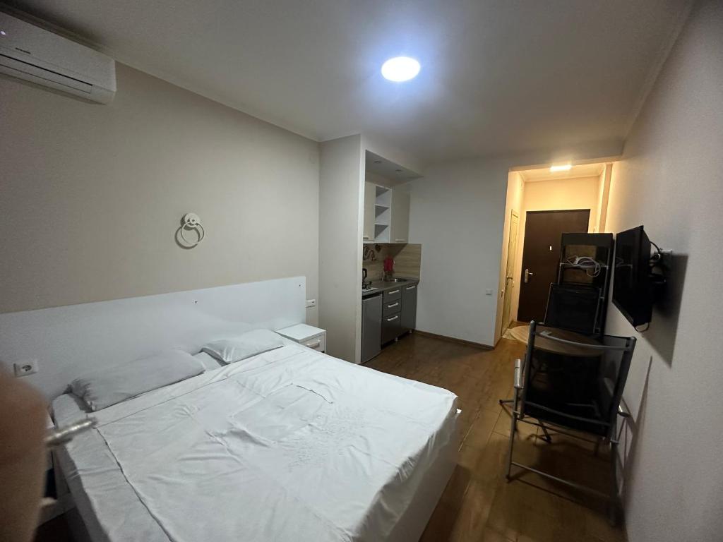 a bedroom with a white bed and a chair at Levanis in Batumi