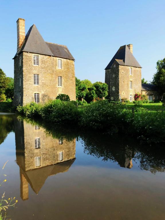 un vieux château avec sa réflexion dans l'eau dans l'établissement Château en Normandie, à Planquery