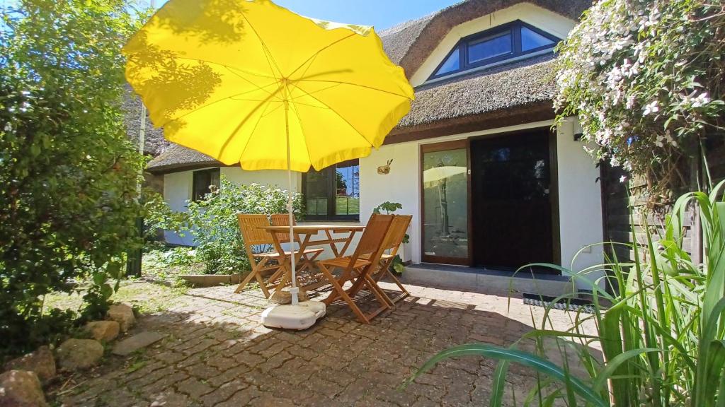 un patio con una mesa y una sombrilla amarilla en Haus 1795 Schwalbennest, en Wustrow