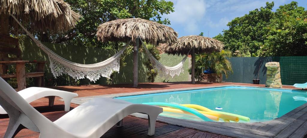 a swimming pool with chairs and umbrellas at Chalés da Cris in Fortim