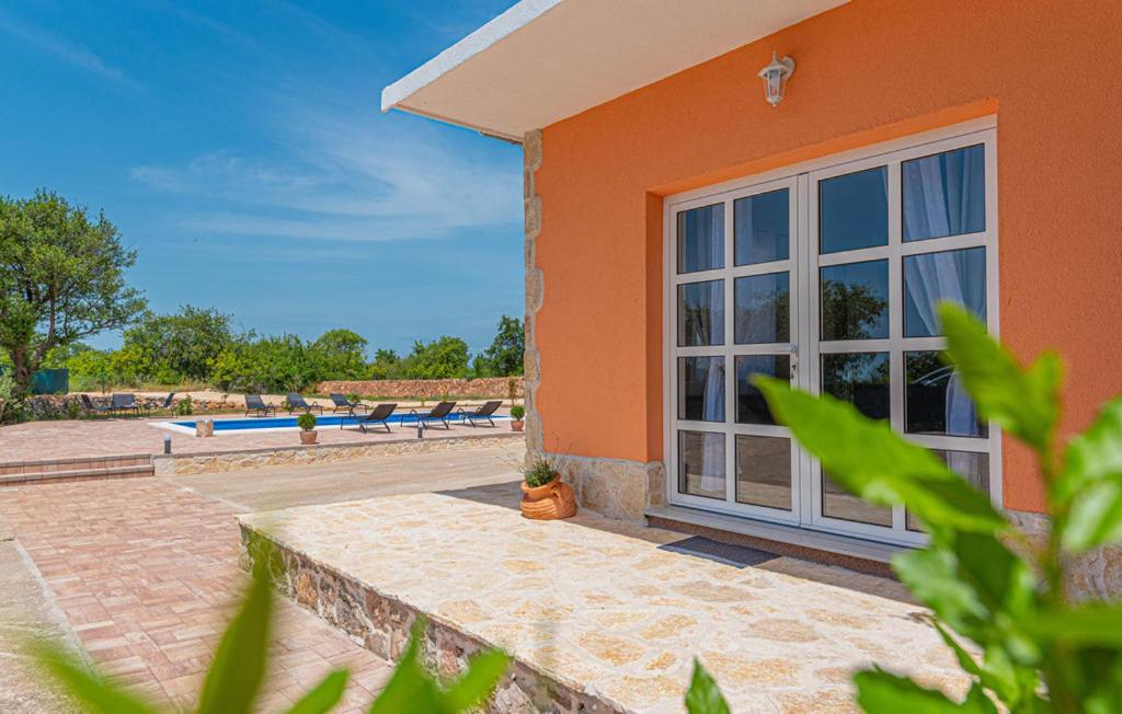 Casa de color naranja con ventana grande y piscina en Iris Holiday home en Trbounje