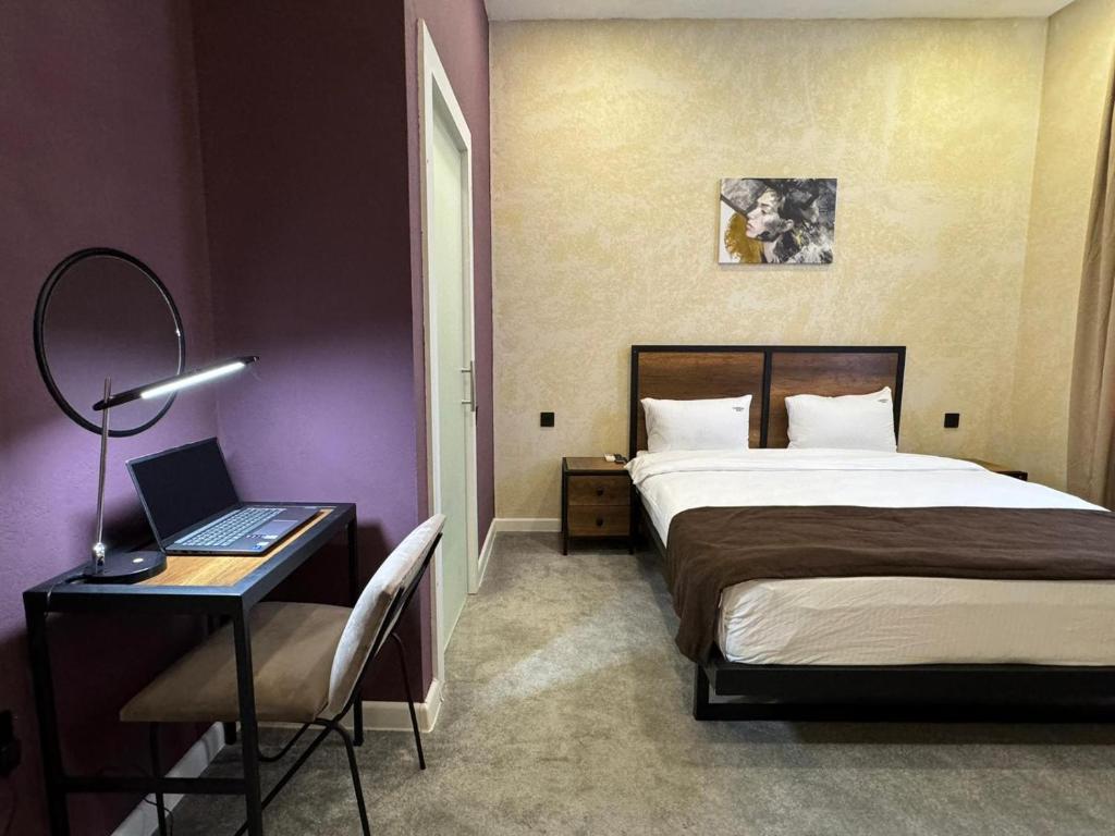 a bedroom with a bed and a desk with a laptop at Liberta Hotel Baku in Baku