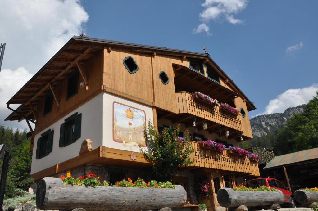 una casa en un tronco con flores delante en CiasaToa en Cortina dʼAmpezzo