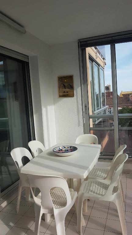 une table blanche et des chaises sur un balcon dans l'établissement Bandol centre ville, port et plage, à Bandol