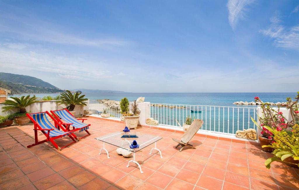 un patio con sillas, una mesa y el océano en Villa Eugenia, en Favazzina
