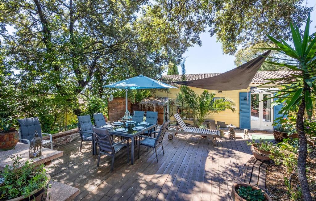 een patio met een tafel en stoelen en een blauwe parasol bij 2 Bedroom Stunning Home In La Crau in La Crau