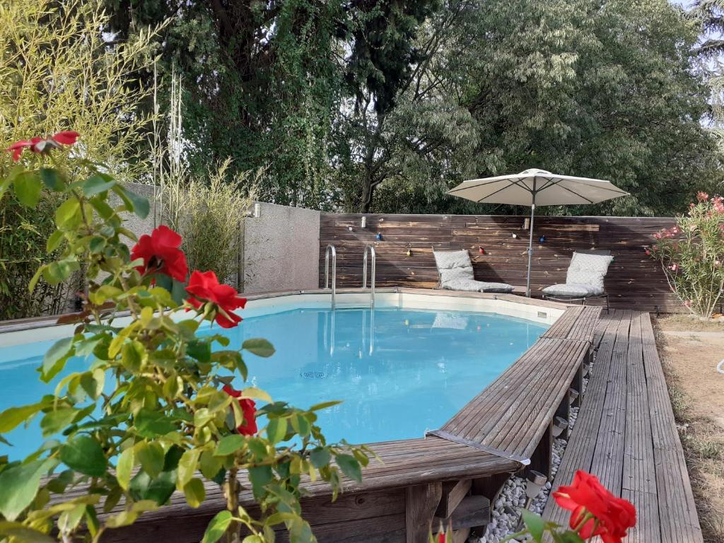 una piscina con banco y sombrilla en Location saisonnière avec piscine et terrasse au pied du luberon, en Lauris