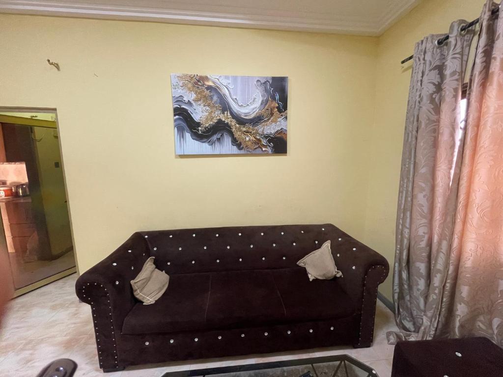 un sofá en una sala de estar con una pintura en la pared en Villa de chez nous, en North Legon