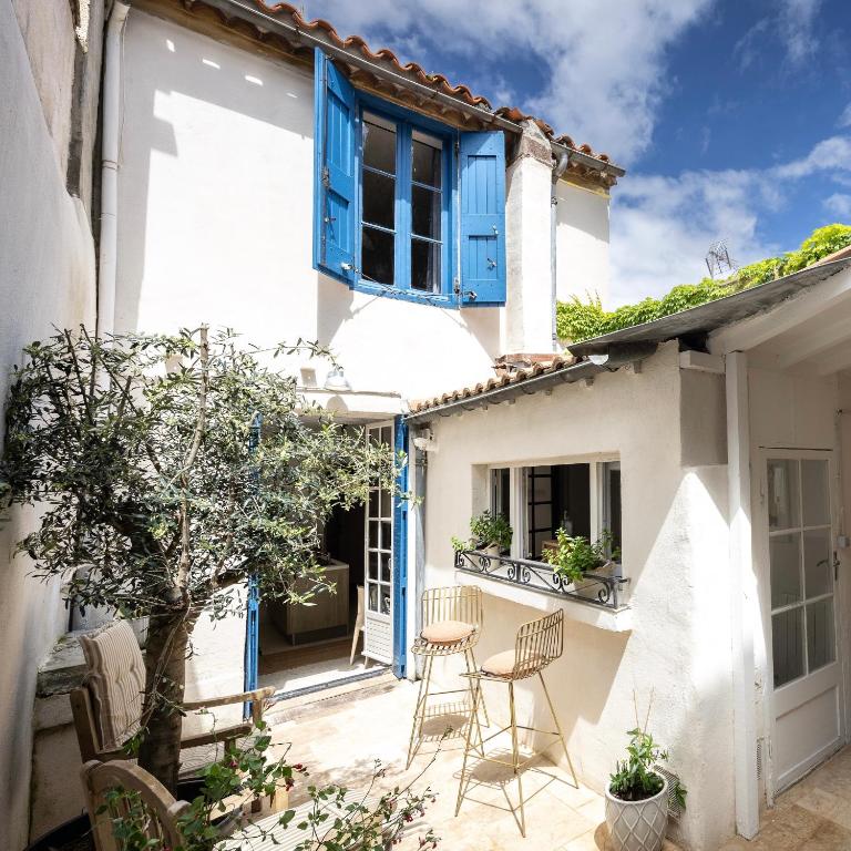 une maison blanche avec des fenêtres et des chaises bleues sur une terrasse dans l'établissement Carcassonne Epicerie, à Carcassonne