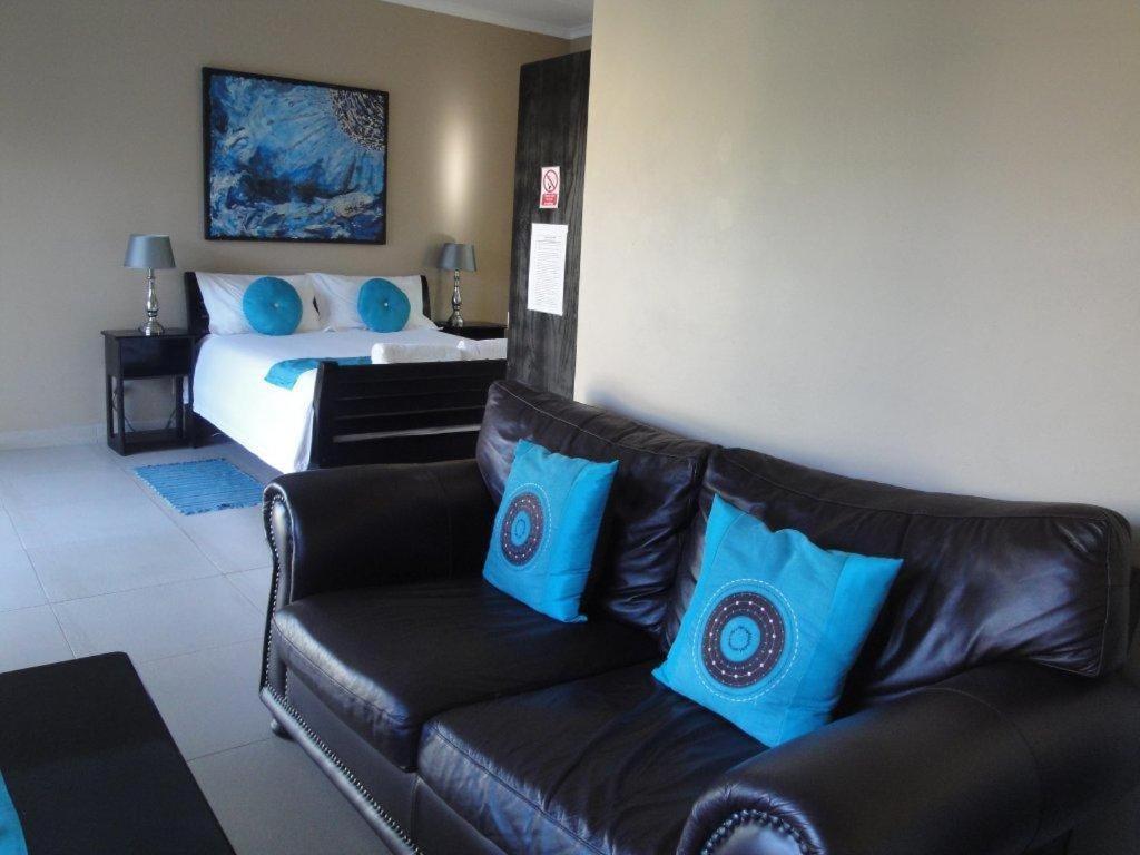 a living room with a leather couch and a bed at Fusion House B&B and Conference Venue SOLAR POWERED in East London