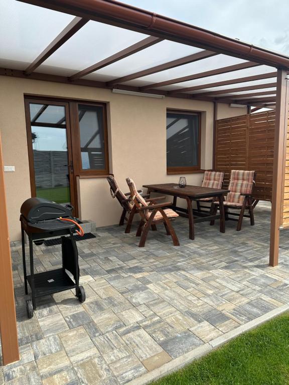 a patio with a table and chairs and a grill at Apartmán Losonci in Nesvady
