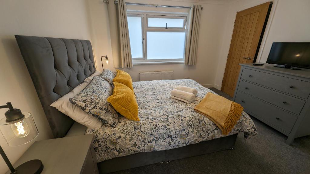 1 dormitorio con cama con almohadas y ventana en Chy Lowen Private rooms with kitchen, dining room and garden access close to Eden Project & beaches en Saint Blazey