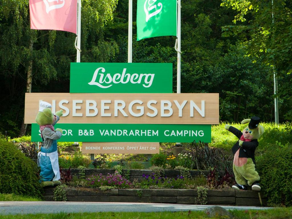 two statues of mascots standing in front of a sign at Lisebergsbyns Stugor in Gothenburg