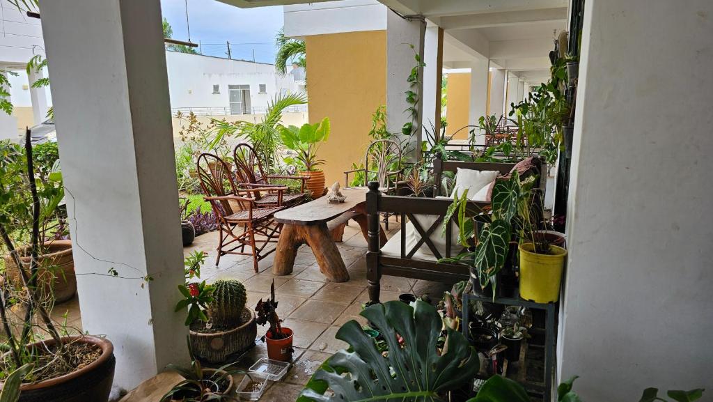 une terrasse avec une table, des chaises et des plantes dans l'établissement Evergreen House - 150Metre Walk To City Mall Nyali, à Mombasa