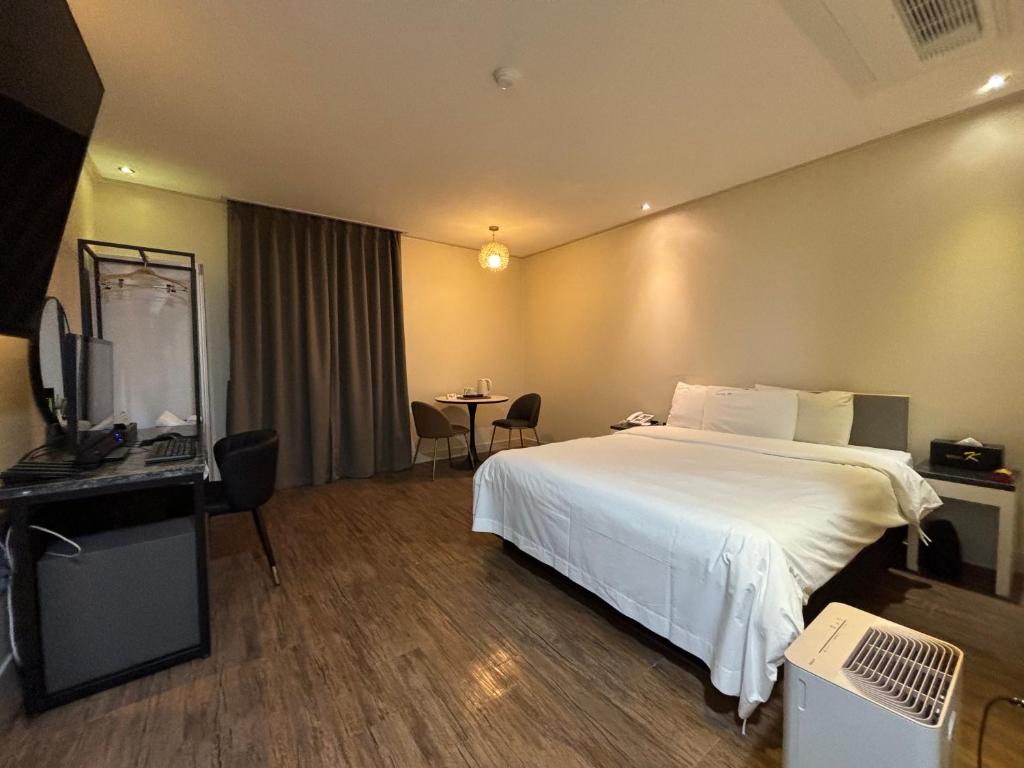 a hotel room with a white bed and a table at Cheonan K Hotel in Cheonan