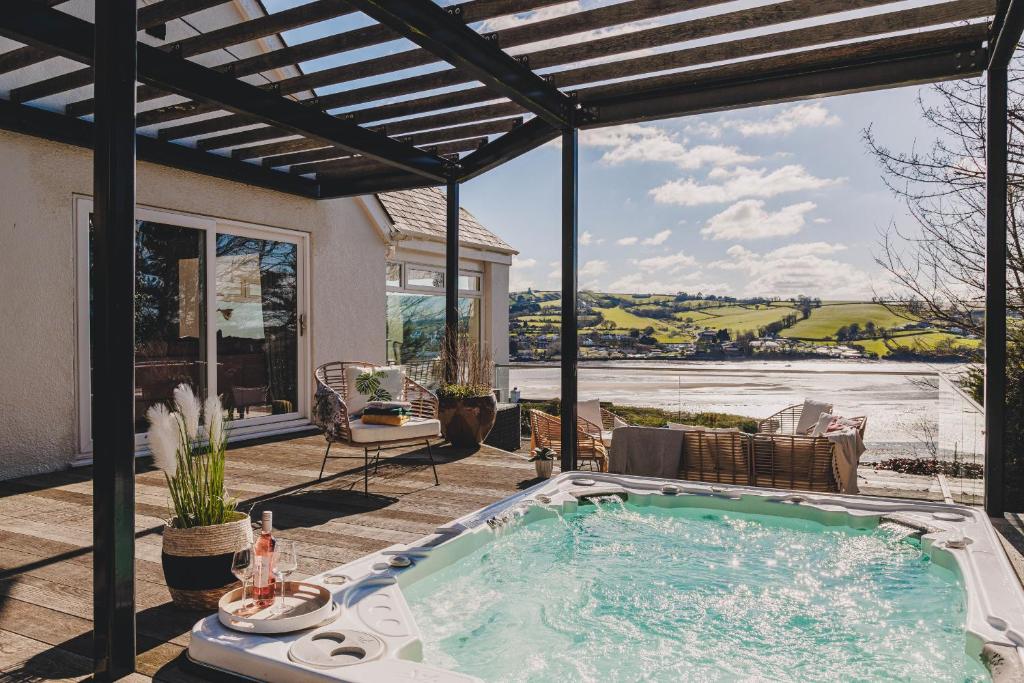 a hot tub on the patio of a house at The Curlews - Waterside, boutique home with 360 panoramic views and 10 person Hyool, Teignmouth in Bishopsteignton