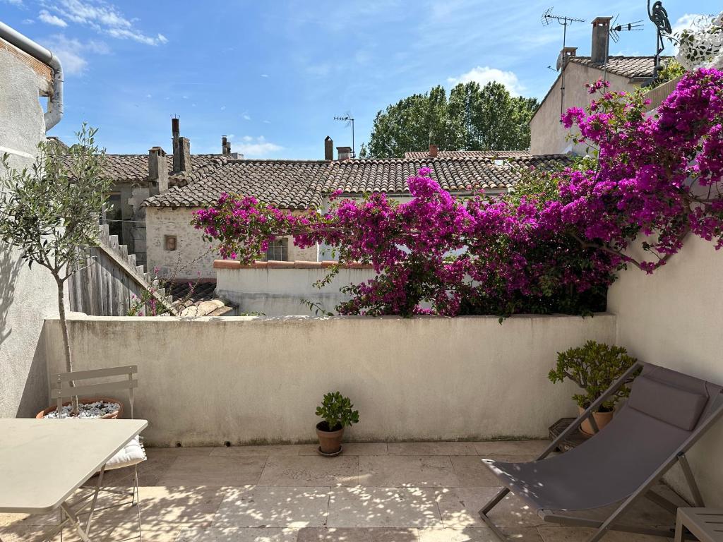 d'un patio orné de fleurs violettes sur un mur. dans l'établissement Appartements 3 étoiles terrasse ou patio intra-muros, à Aigues-Mortes