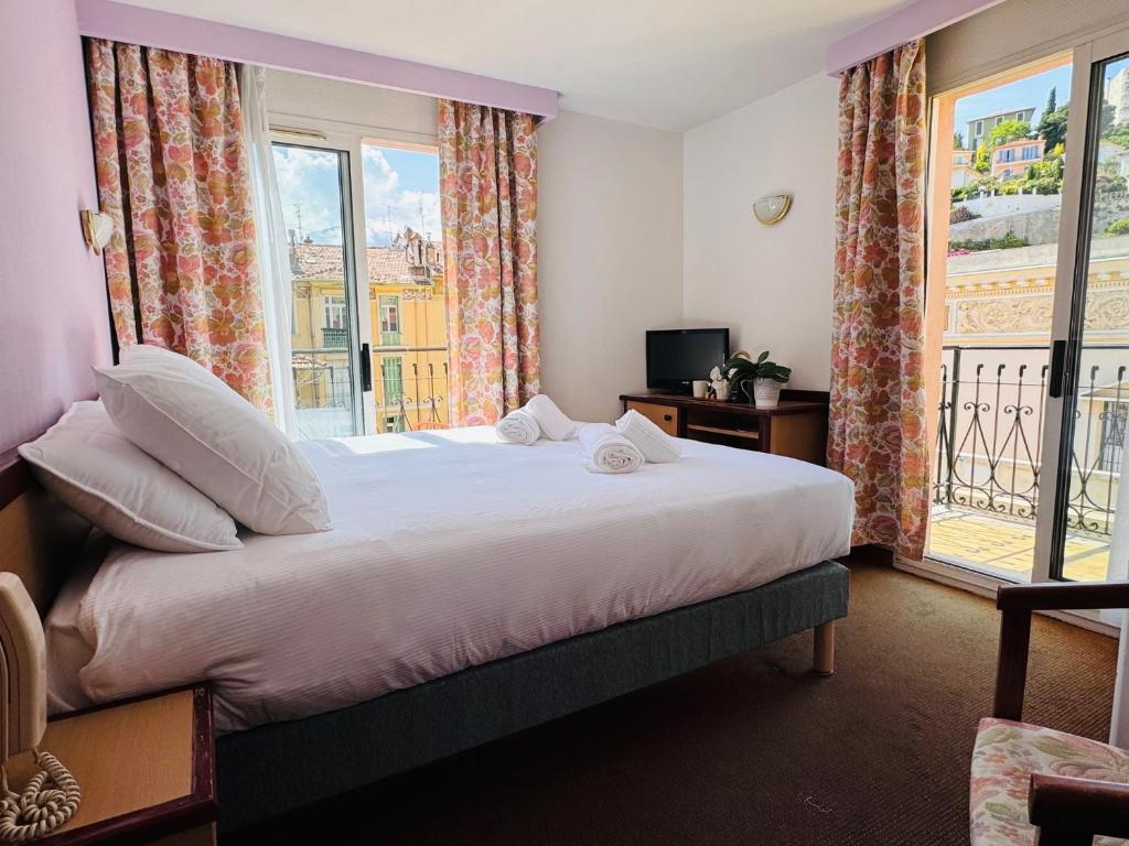 sypialnia z dużym łóżkiem i oknem w obiekcie Hôtel Narev's w Mentonie