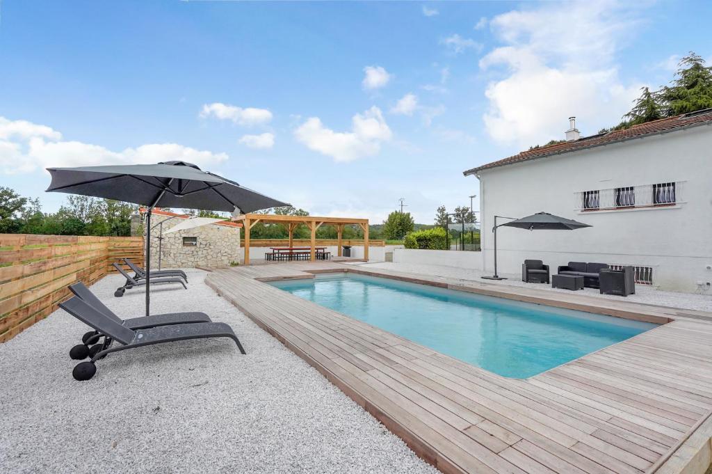 a pool with two chairs and an umbrella next to a house at Villa Rose - Padel - Piscine - Cinéma & Poker Room in Saint-Jory