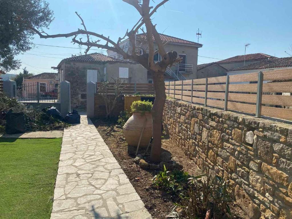 a tree in a yard next to a stone wall at Quiet Guest house in Moúdhros