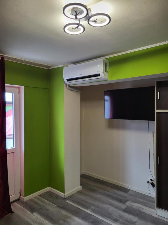 een kamer met groene muren en een flatscreen-tv bij Garsoniera DUE in Petroşani