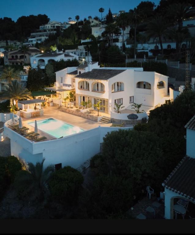 a large white house with a swimming pool at night at Casa El Sueño in Jávea