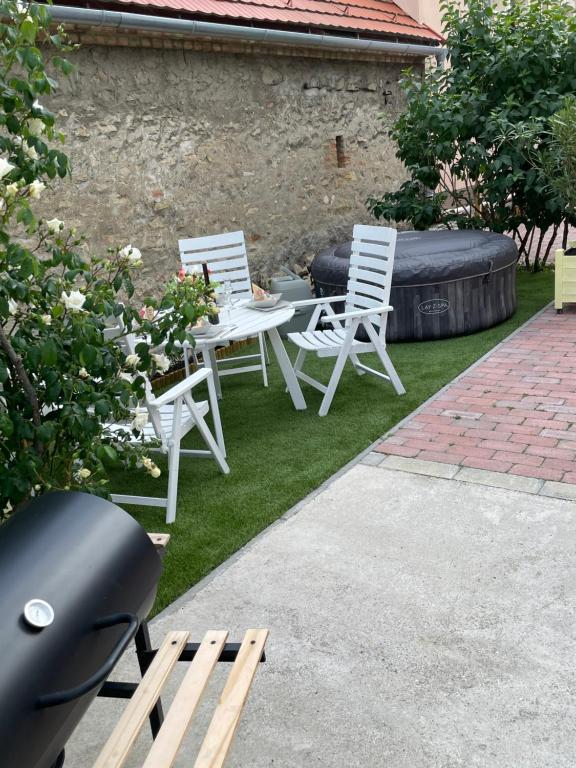 two white chairs and a table in a yard at Bakonyi Porta Olaszfalu in Olaszfalu