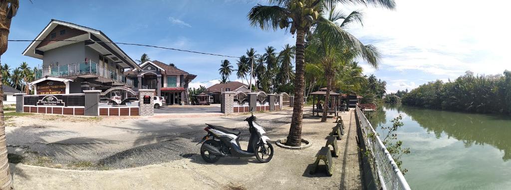 Una motocicleta estacionada junto a una casa junto a un río. en Airport Kota Bharu Roomstay & Riverside Homestay, en Kota Bharu