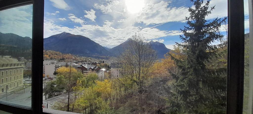 une fenêtre avec vue sur la ville et les montagnes dans l'établissement La Briancelle, à Briançon