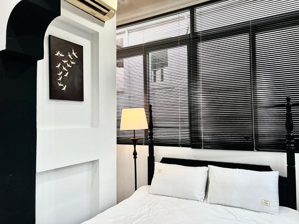 a bedroom with a bed and a window with blinds at Indochine Design Apartment Hotel 5 - Hanoi Old Quarter in Hanoi