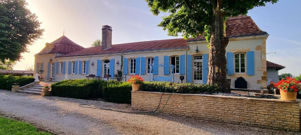 une maison avec des fenêtres bleues et un mur en briques dans l'établissement chartreuse st Cernin, à Bergerac