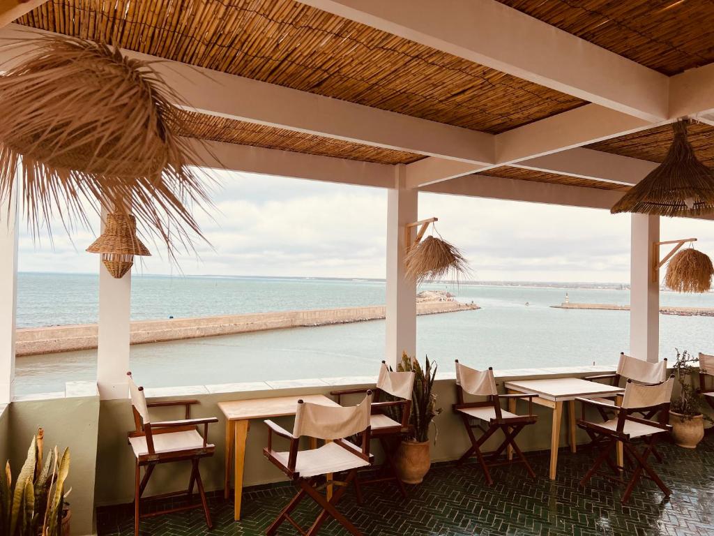 restauracja ze stołami i krzesłami oraz widokiem na ocean w obiekcie Art riad au bord de la mer 2 w mieście Al-Dżadida