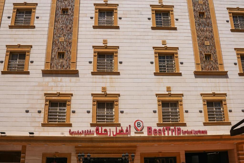 a tall white building with a red sign on it at Best Trip Serviced Apartments in Jeddah